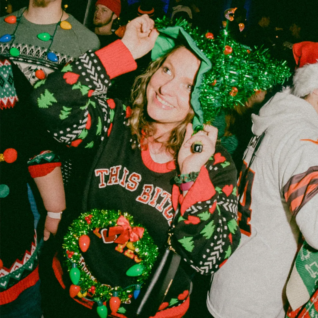 girl dressed in ugly sweater with christmas tree hat at the christmas bar crawl